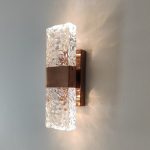 Crystal rose gold wall light switched on showing warm white ambient glow through textured glass panel