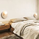 Pair of travertine round wall lights installed as bedside reading lights on both sides of bed