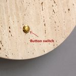 Close-up of brass push button switch on yellow travertine stone wall light surface