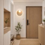 Travertine round wall light mounted in BTO foyer with wabi sabi interior — wooden door, shoe cabinet, and indoor plant