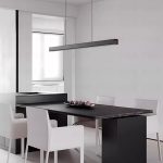 Black LED linear pendant light with walnut end cap above dining or kitchen island table
