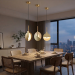 Solaris dining table pendant light in matt gold installed above a modern dining table