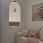 Modern pendant lamp installed in arched wall niche with warm ambient glow